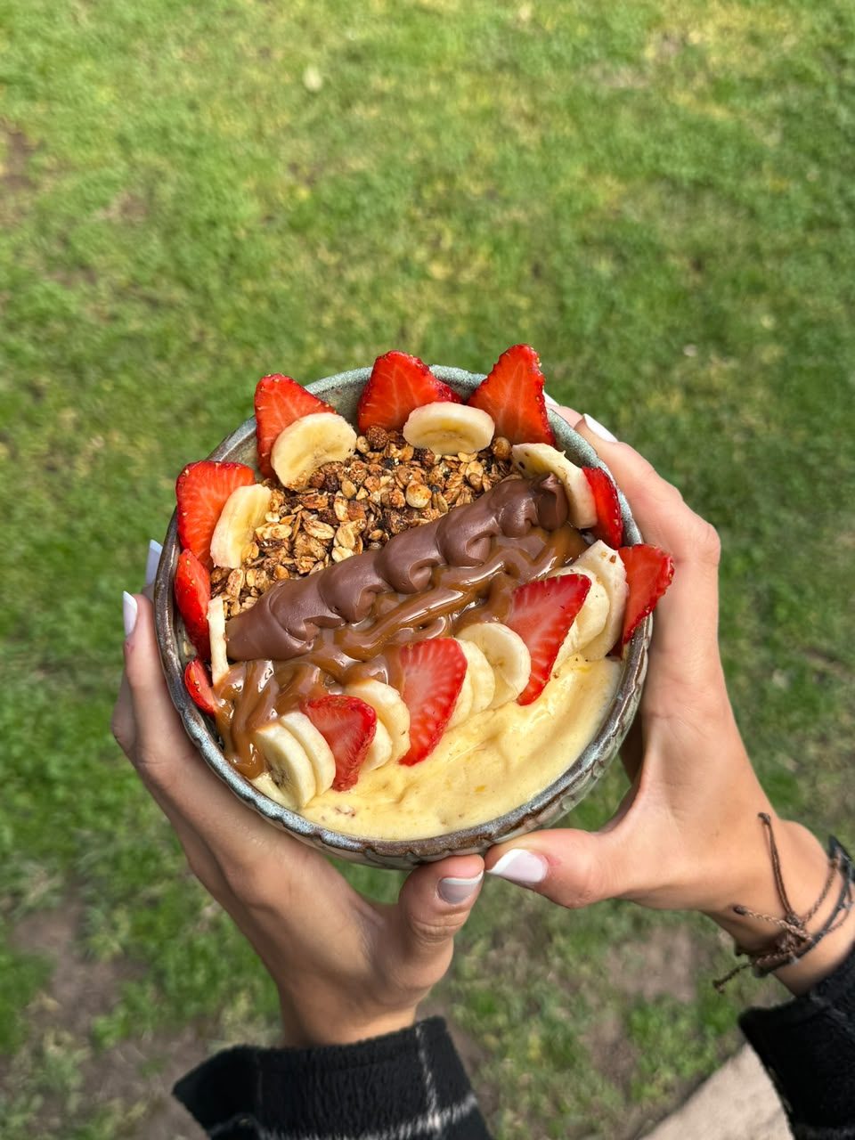 Mano sosteniendo un smoothie bowl BORA al aire libre